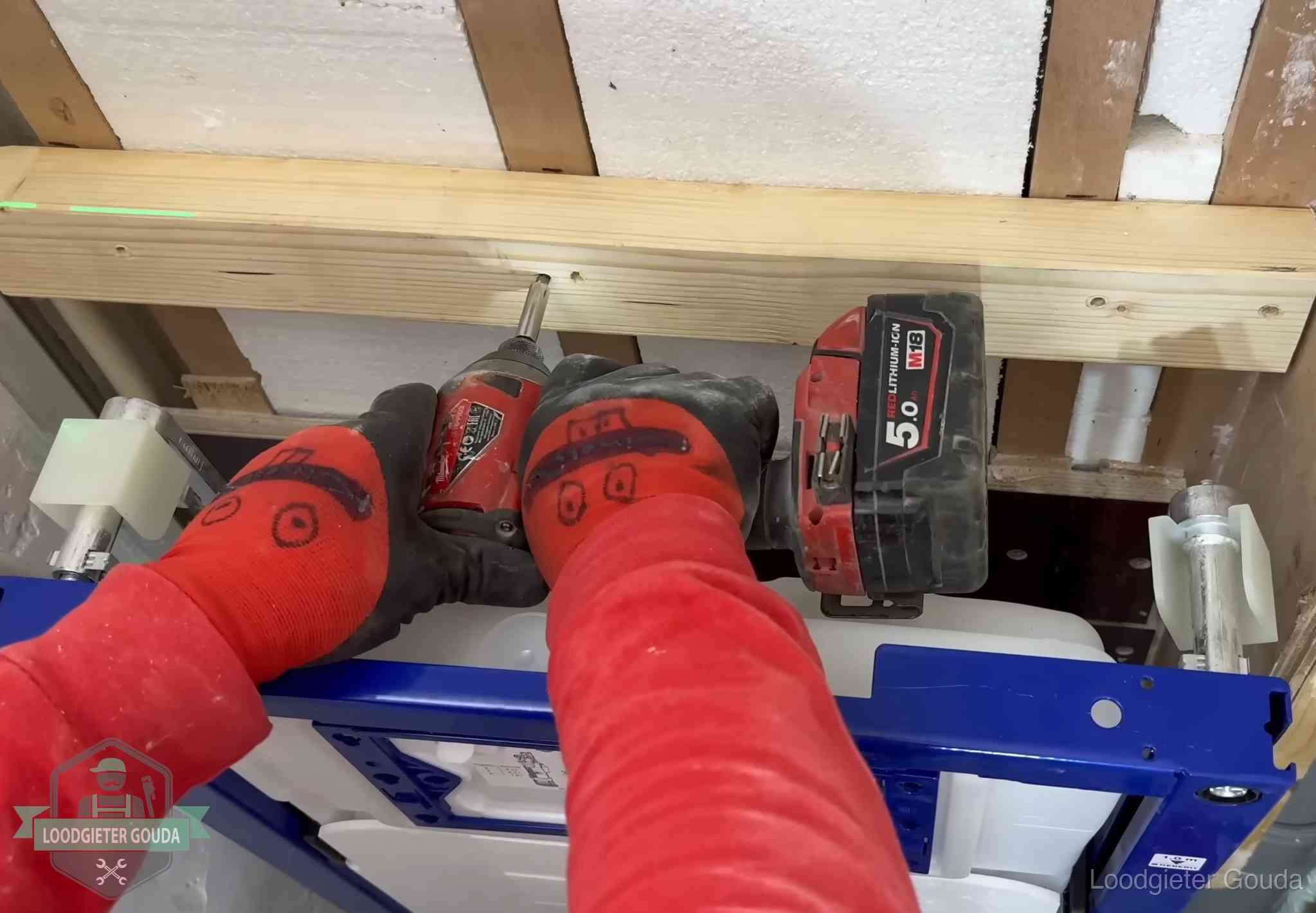 Monteur bevestigt een inbouwreservoir voor een hangend toilet in Gouda