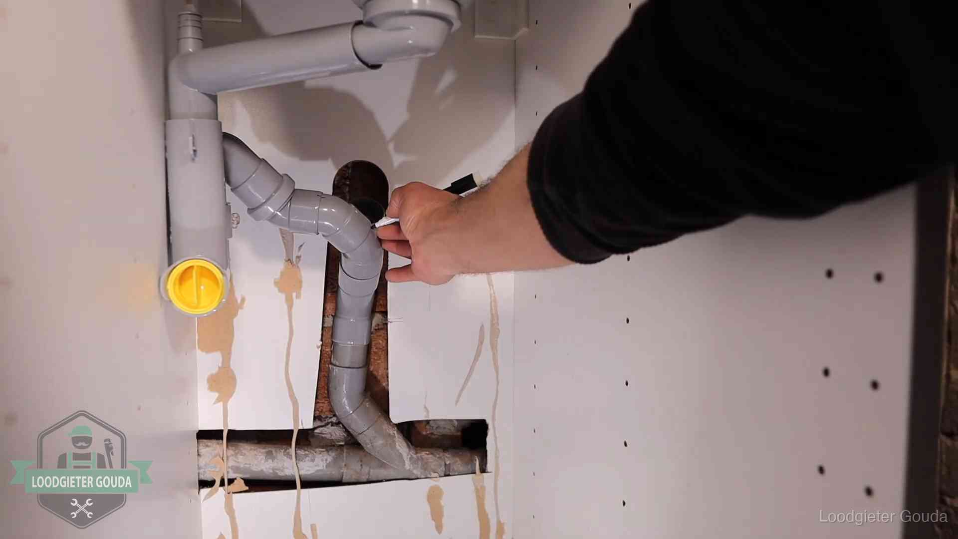 Loodgieter markeert een pvc-afvoerbuis onder een gootsteen in Gouda