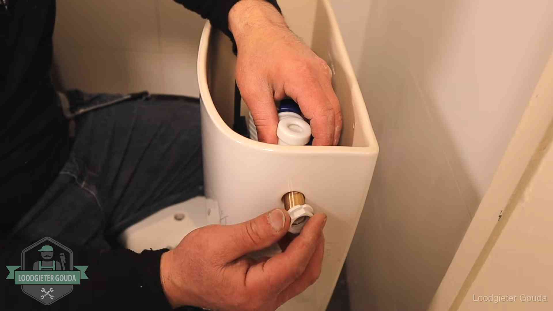 Loodgieter monteert de vlotterkraan van een stortbak bij een toilet in Gouda