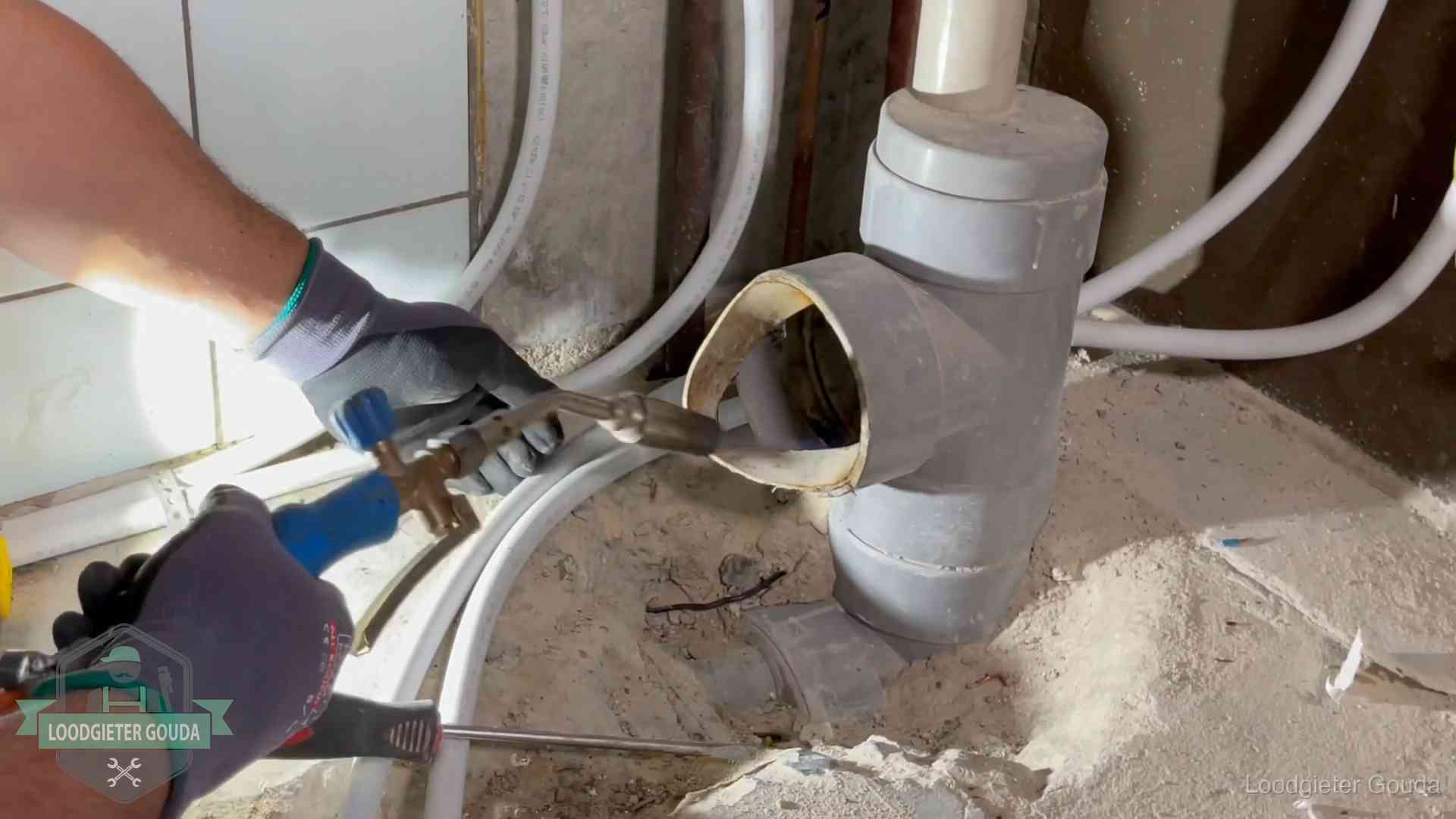 Loodgieter werkt met brander en messing kraanwerk aan leidingen in Gouda