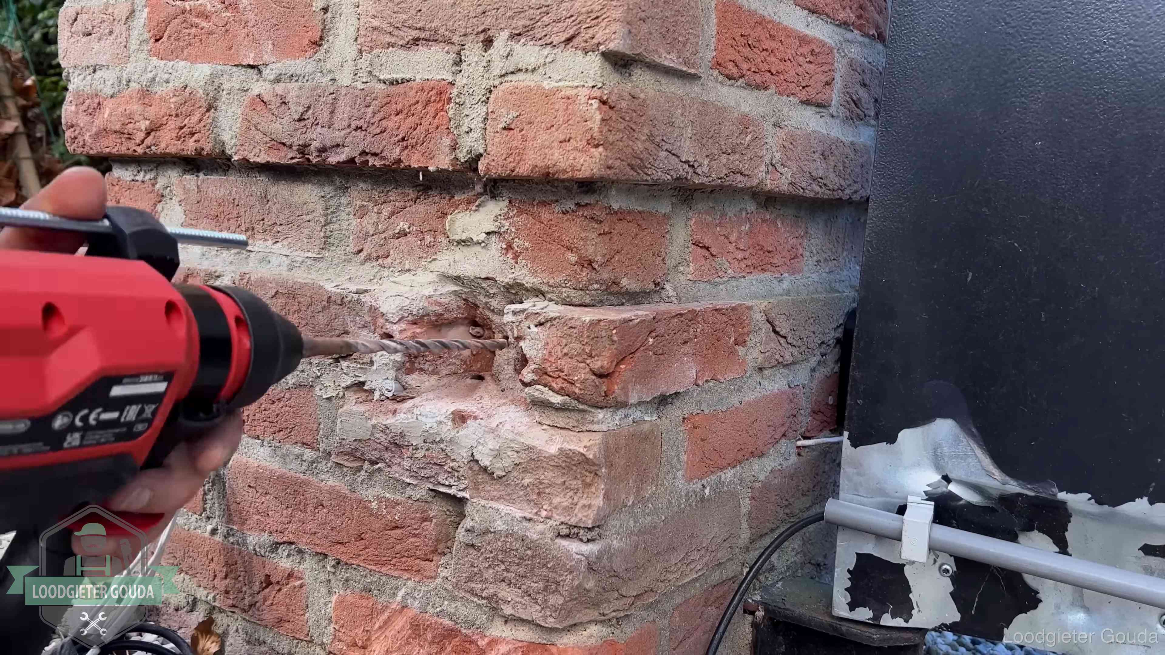Vakman boort in de buitenmuur van een woning in de regio Gouda