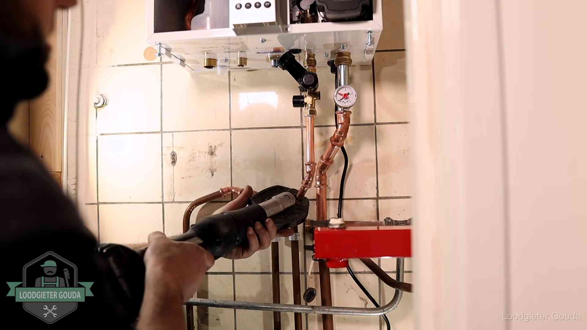 Monteur werkt aan de leidingen onder een cv-ketel in Gouda