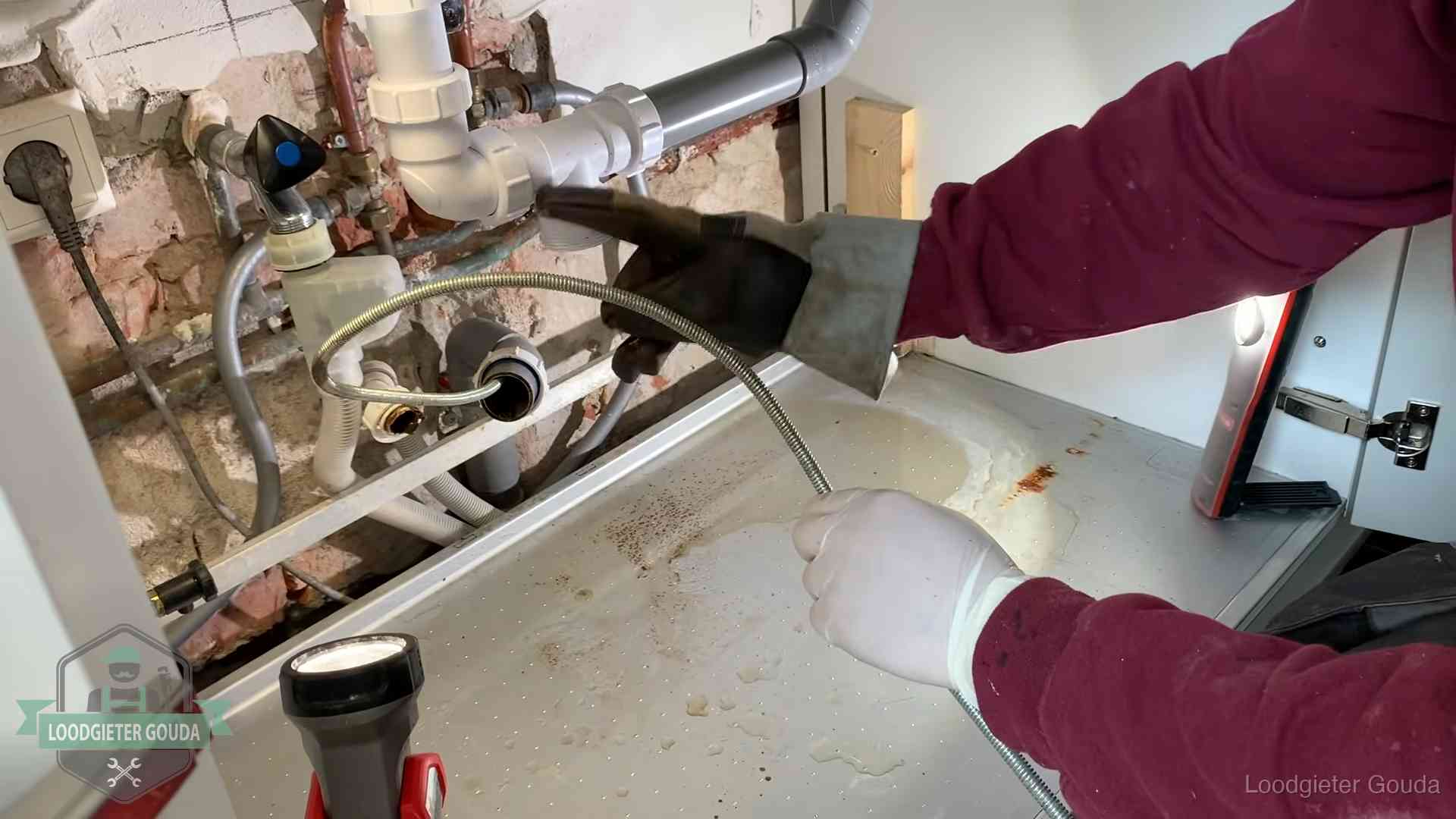 Spiraal of hogedruk in Gouda Ontstoppingsveer gaat in een geopende sifonaansluiting onder het aanrecht in Gouda