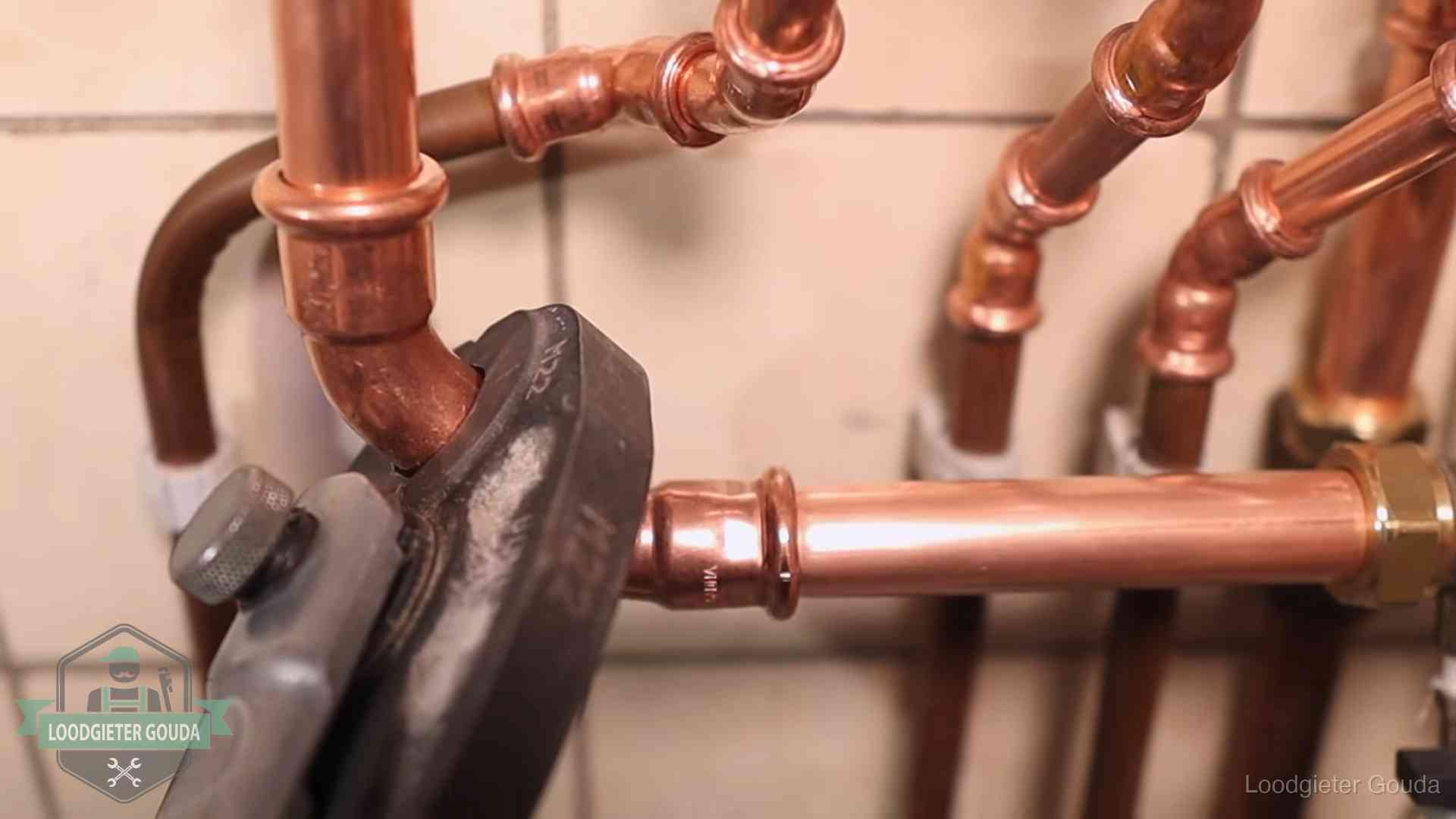 Persmachine perst een koperen fitting op nieuw leidingwerk in Gouda