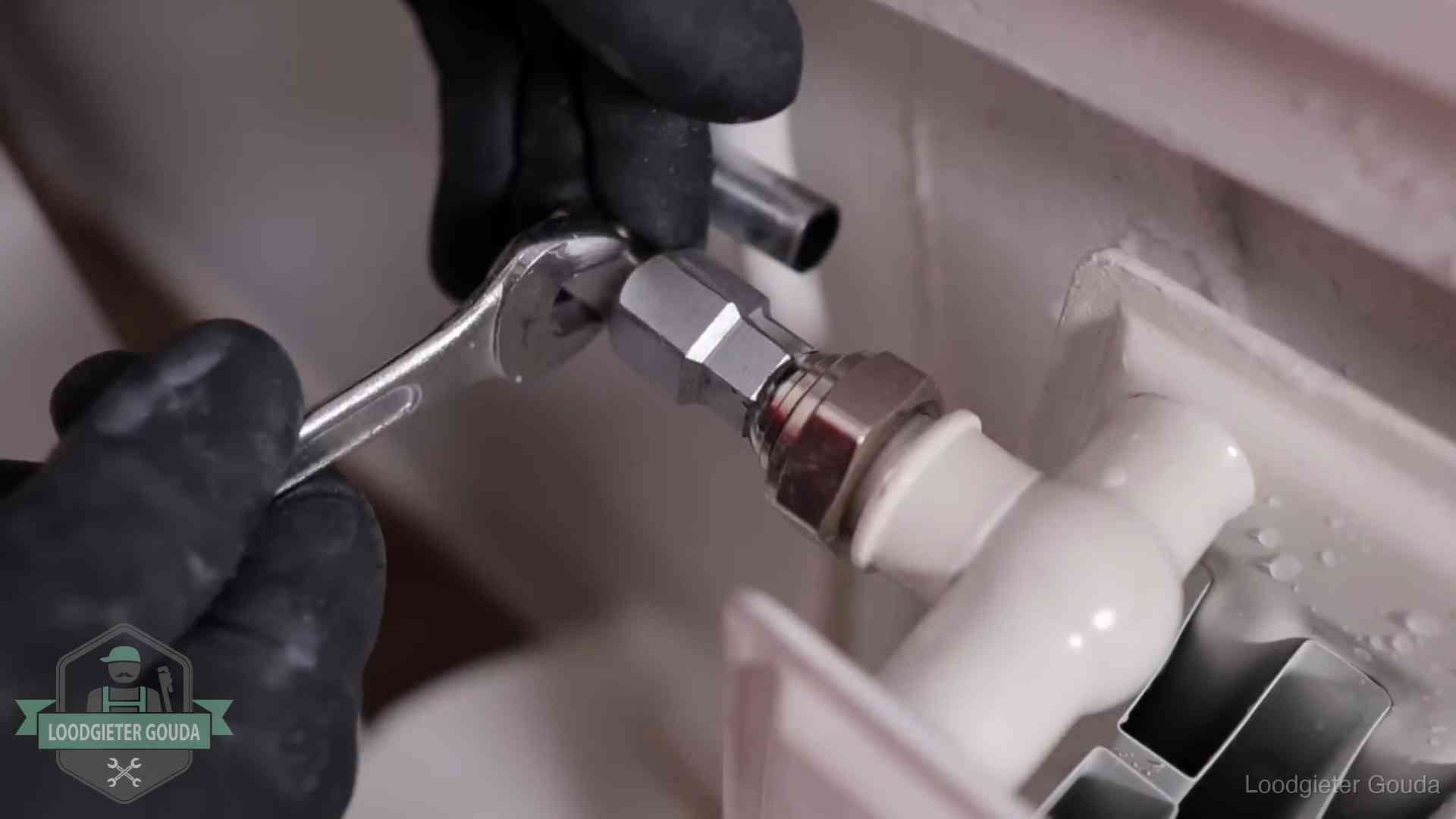 Steeksleutel draait een wartelkoppeling op een radiatorkraan aan in Gouda