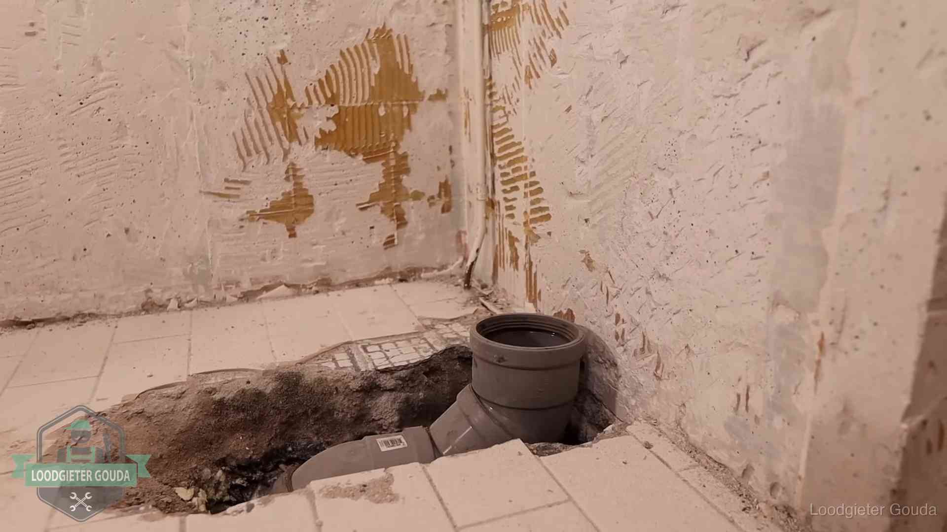 Verzakt riool herstellen in Gouda Opengebroken vloer met een nieuwe pvc-rioolbocht in een gegraven sleuf in Gouda