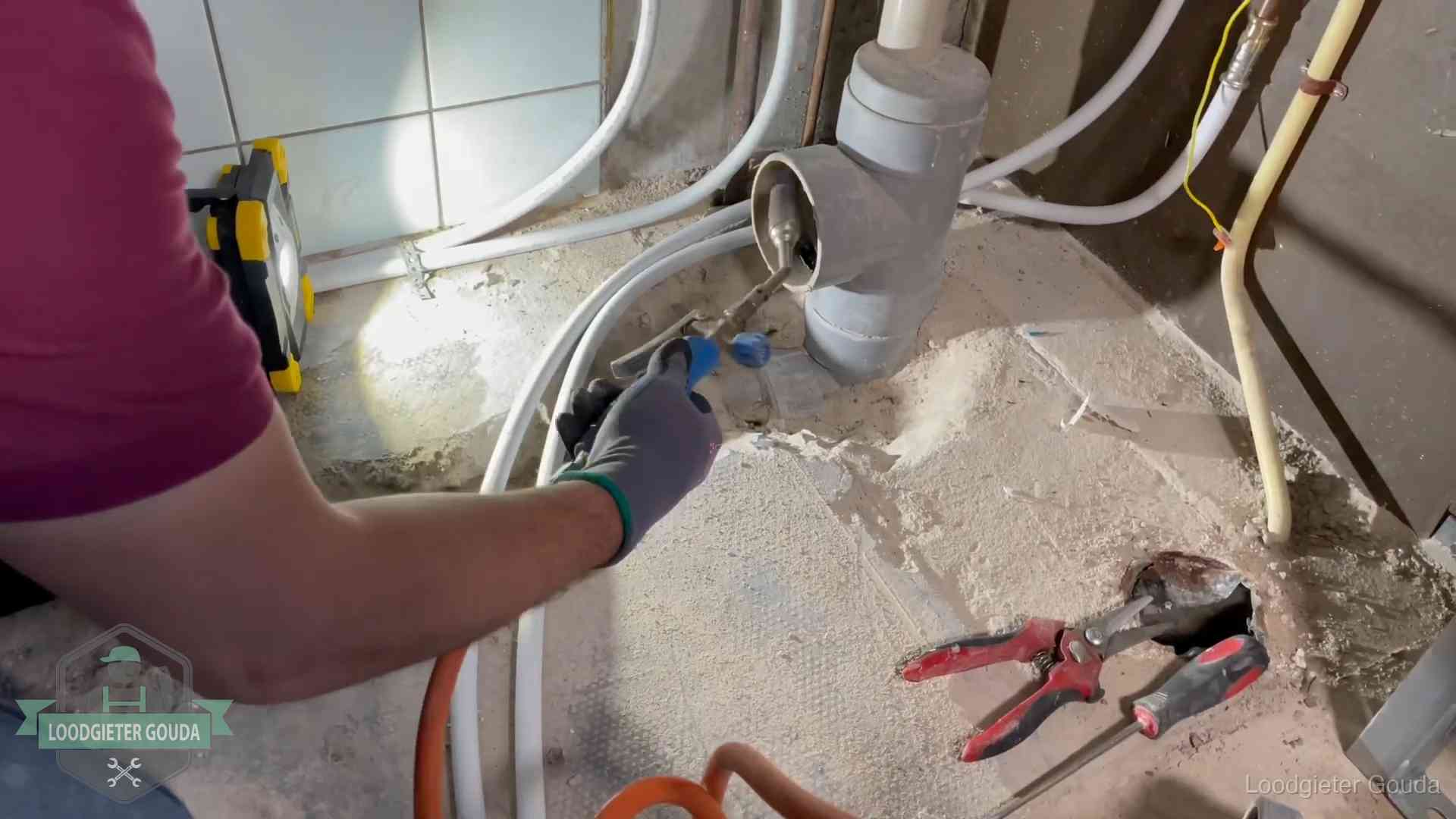Loodgieter werkt aan leidingen bij een pvc-standleiding in een appartement in Gouda