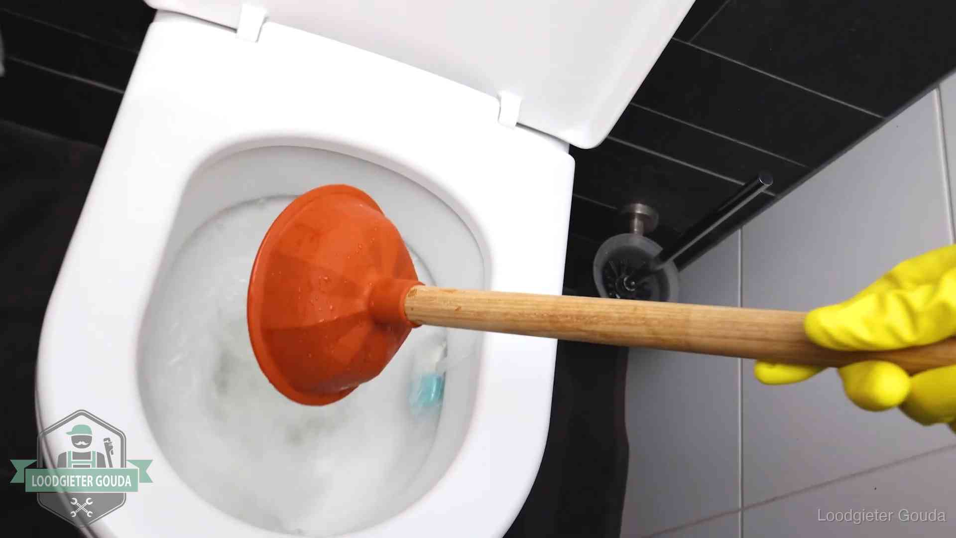 Plopper wordt in de wc-pot gedrukt bij het ontstoppen van een toilet in Gouda
